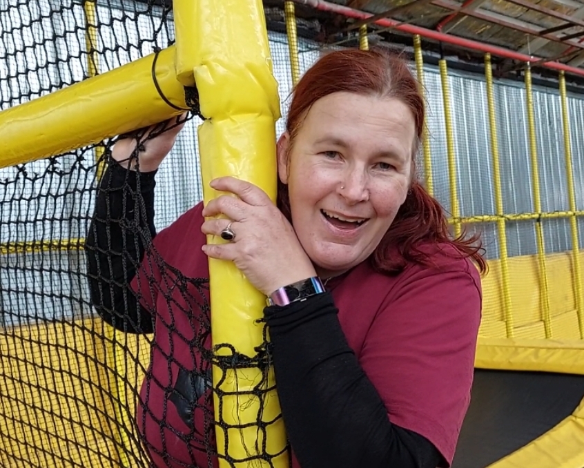 woman with red hair clutching a yellow pole and laughing