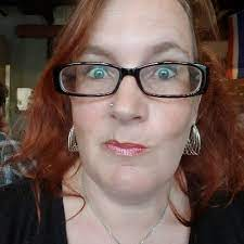 image of woman pulling quizzical face with glasses and red hair. 
